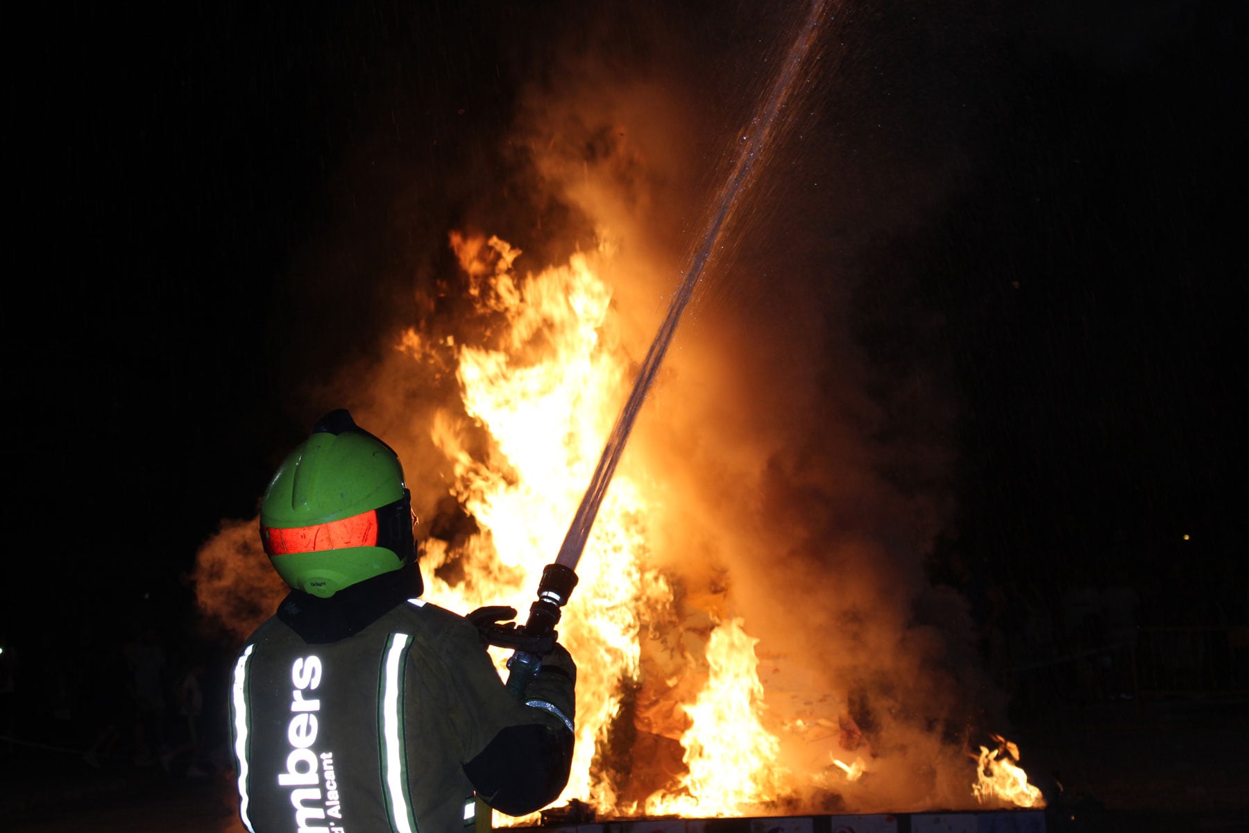 Un bombero controlando la Foguera de la Zona Nord