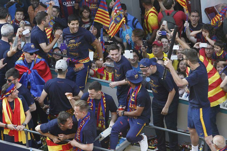 Los jugadores del FC Barcelona, el uruguayo Luis Suárez (2i), Jordi Alba, y el argentino Leo Messi (3d) rien con Gerard Piqué (d), durante la celebración con la afición del nuevo título de Liga, el vigésimo cuarto que gana el equipo, en un recorrido lleva