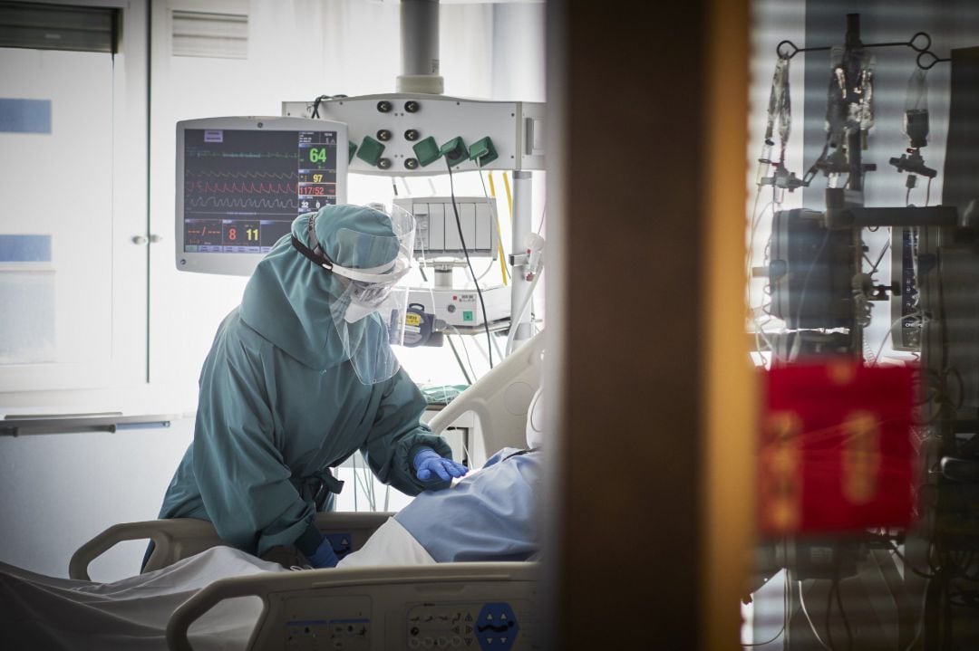 Un trabajador sanitario atiende a un paciente en una camilla de la UCI de la Clínica Universidad de Navarra, en Pamplona, Navarra, (España), a 10 de noviembre de 2020