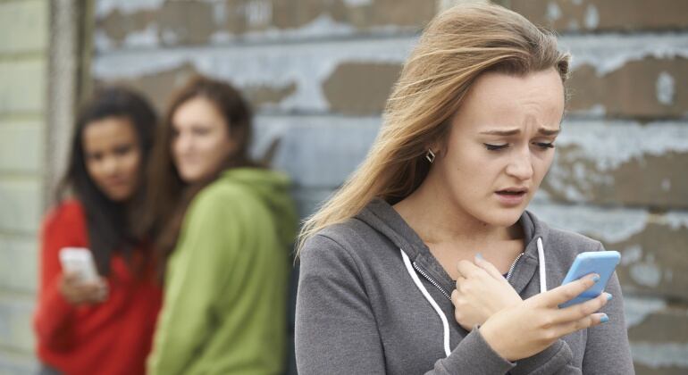 Imagen de una chica asustada mirando su teléfono móvil con expresión de agobio.