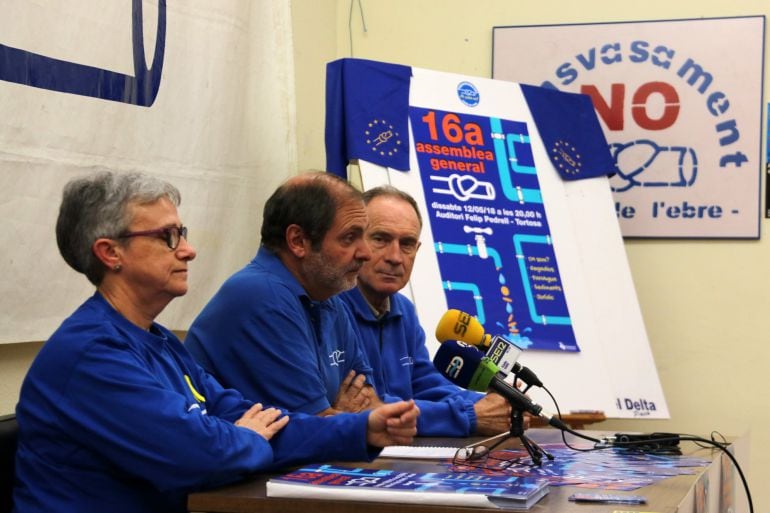 Els portaveus de la PDE Matilde Font, Joan Antoni Panisello i Manolo Tomàs, amb el cartell de la setzena assemblea general de l&#039;entitat, al fons.