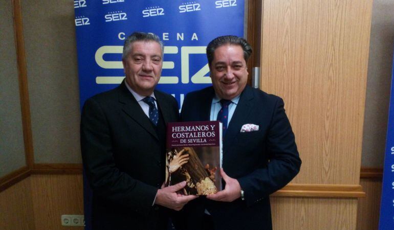 Pepe Carrasco, a la izquierda, y Manolo Vega posan con su libro enciclopédico &#039;Hermanos y Costaleros de Sevilla&#039; en el estudio de Cruz de Guía