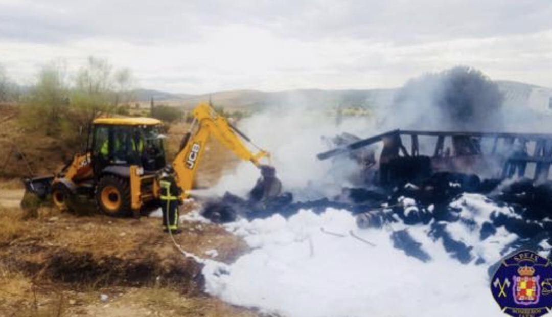 Una grúa trabaja en la retirada de los restos del camión incendiado.