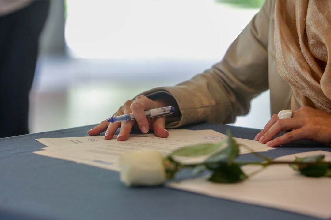 Detalle de una de las contrayentes firmando durante la celebración de su boda, oficiada por el concejal de Urbanismo del Ayuntamiento de Madrid, Mariano Fuentes.