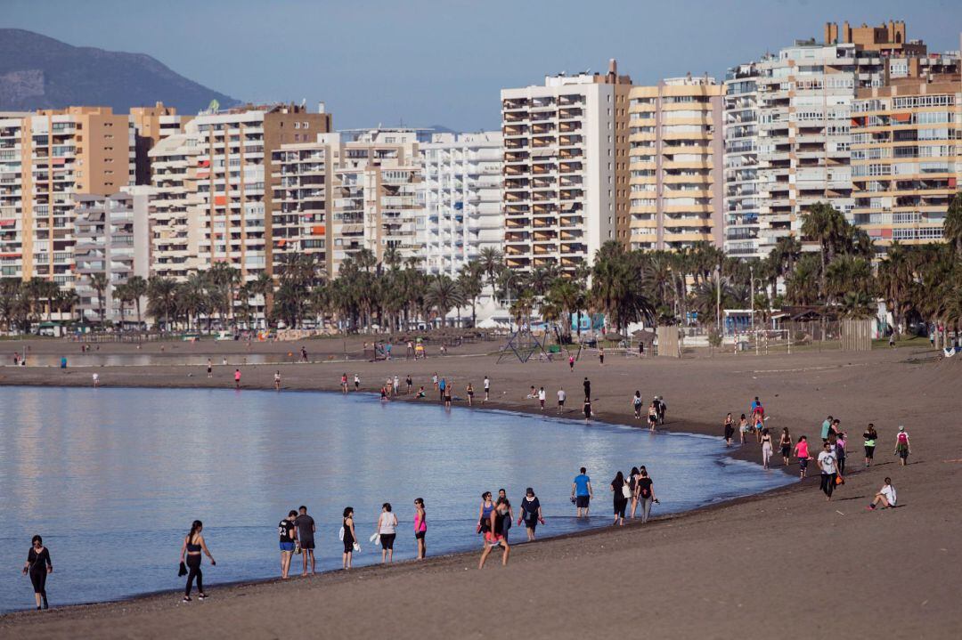 Numerosas personas caminan por la orilla de la playa de la Malagueta de Málaga, dentro de la nueva normativa que permite hacer actividades deportivas y pasear en dos franjas horarias, cuando se cumple 49 días de confinamiento en el estado de alarma decretado por el Gobierno por la crisis de la COVID-19
