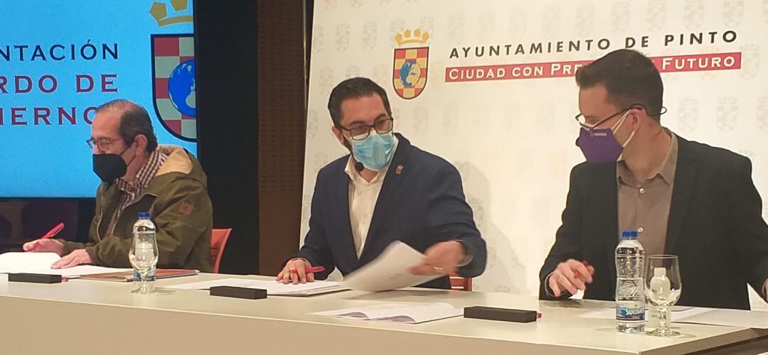 El socialista Diego Ortiz, (en el centro), junto con los portavoces de Unidas Podemos (izquierda) e Isaac López (derecha) firmando el acuerdo de gobierno en Pinto.