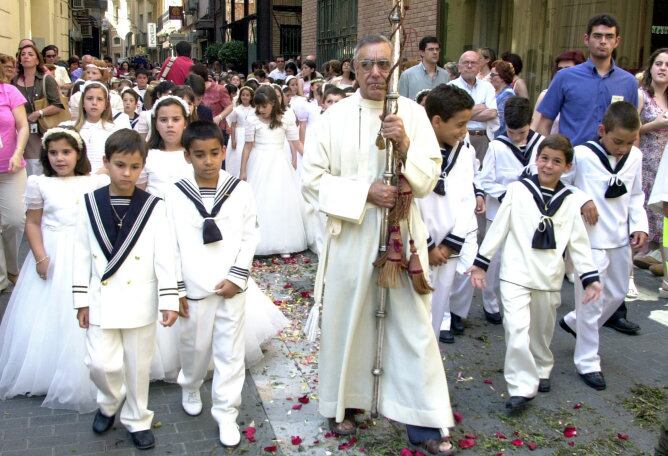 Un grupo de niños, con sus trajes de primera comunión, caminan junto a un sacerdote por las calles de Murcia durante la procesión del Corpus Christi (Imagen de archivo)