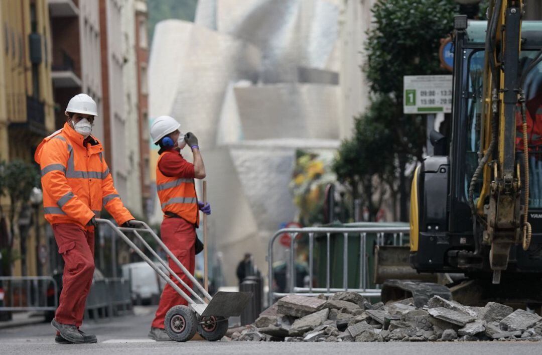Dos operarios trabajan en la obra de una calle cerca del Museo Guggenheim.