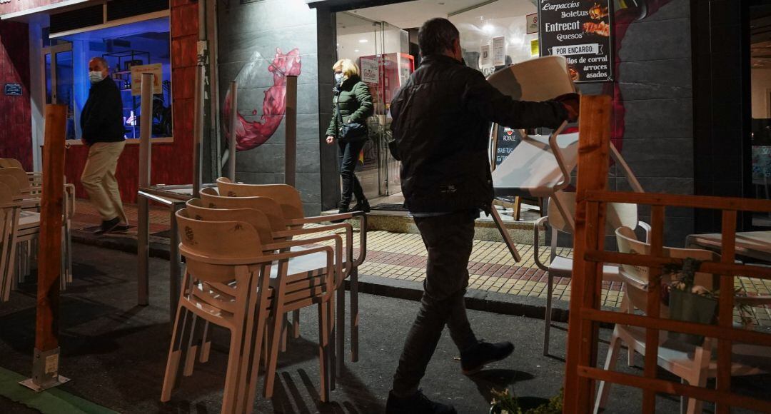Un trabajador de un restaurante de Salamanca recoge la terraza de su establecimiento la noche en la que la ciudad.
