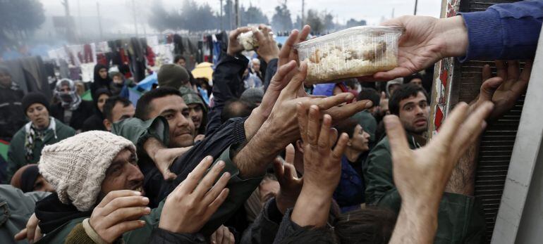 Refugiados y migrantes se avalanzan para coger un recipiente con comida durante el reparto de alimentos en el campo de refugiados de Idomeni, situado en la frontera entre Grecia y Macedonia.