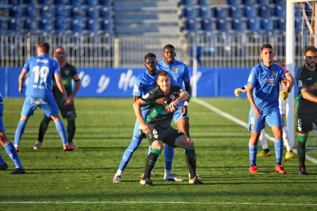 El pivote del Elche Manuel Sánchez es agarrado por un jugador del Fuenlabrada