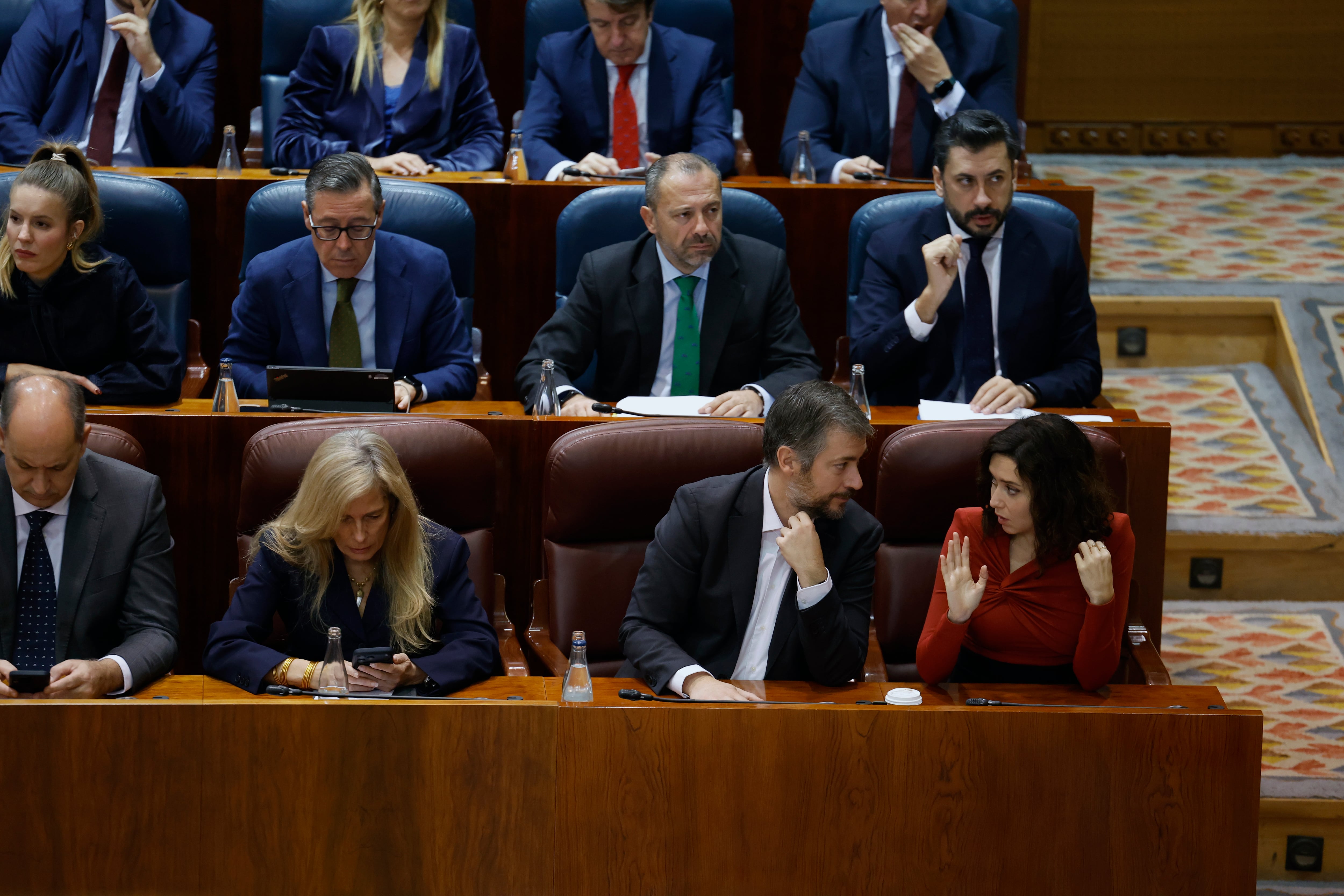 MADRID, 19/12/2025.- La presidenta regional, Isabel Díaz Ayuso (d), conversa con el consejero de Presidencia, Justicia y Administración Local, Miguel Ángel García Martín (2d), durante la segunda jornada del último pleno del año en el que se aprueban definitivamente los Presupuestos de la Comunidad. EFE/