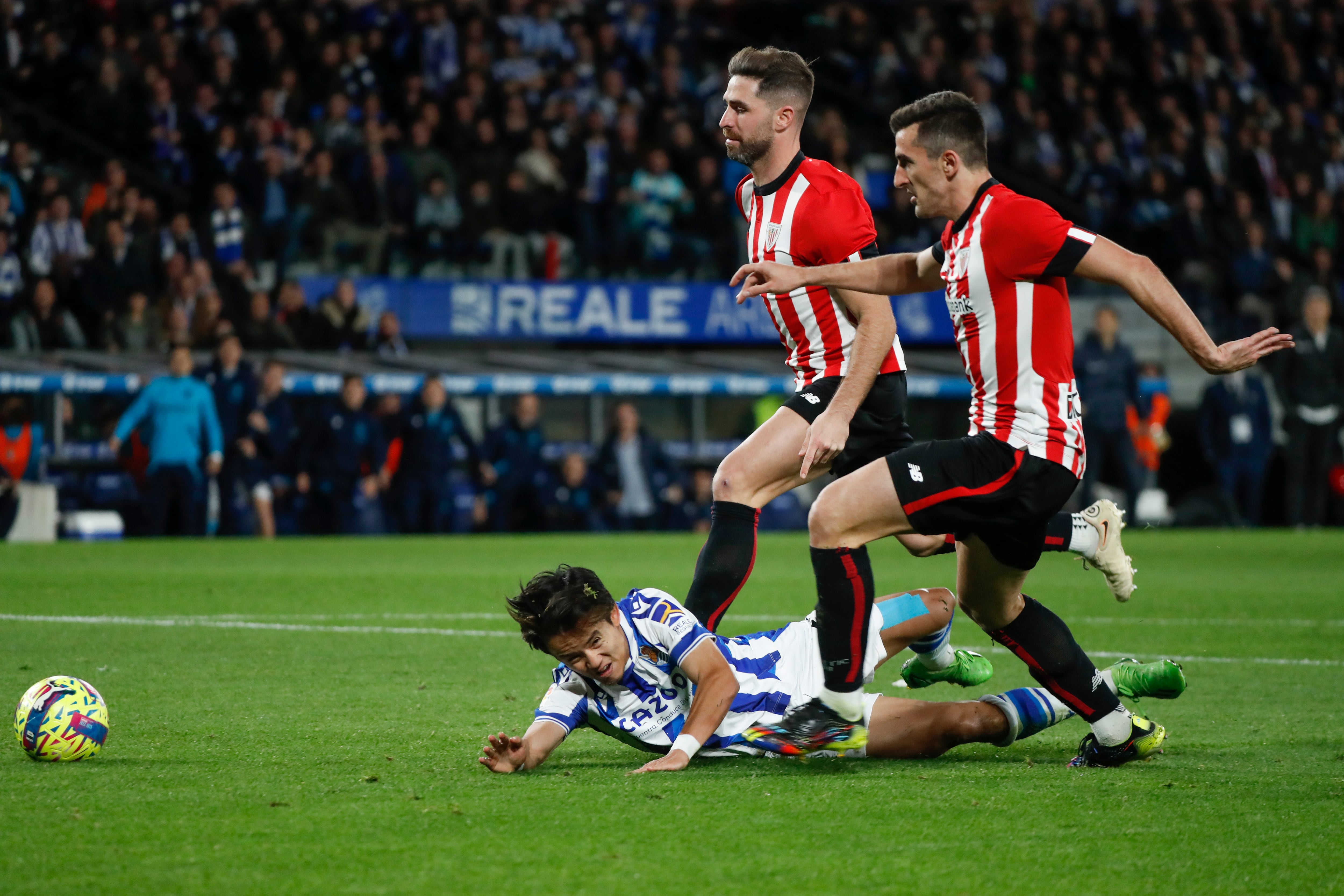 SAN SEBASTIÁN, 14/01/2023.- El delantero japonés de la Real Sociedad Takefusa Kubo (i) cae derribado por Yeray Álvarez (c), del Athletic, durante el partido de la jornada 17 de la LaLiga Santander que Real Sociedad y Athletic de Bilbao disputan este sábado en el Reale Arena, en San Sebastián. EFE/ Javier Etxezarreta
