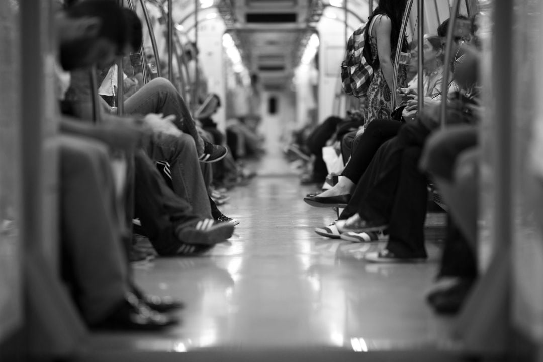 Gruupo de personas en el metro, mirando sus dispositivos móviles