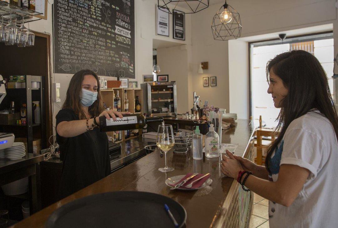 Una camarera sirve una copa de vino a una clienta