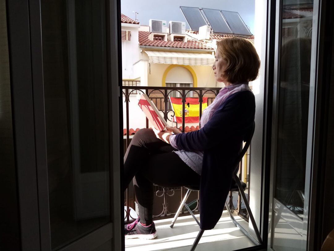 Una mujer disfruta de la lectura, en el balcón de su casa, durante el confinamiento. Cabra, Córdoba