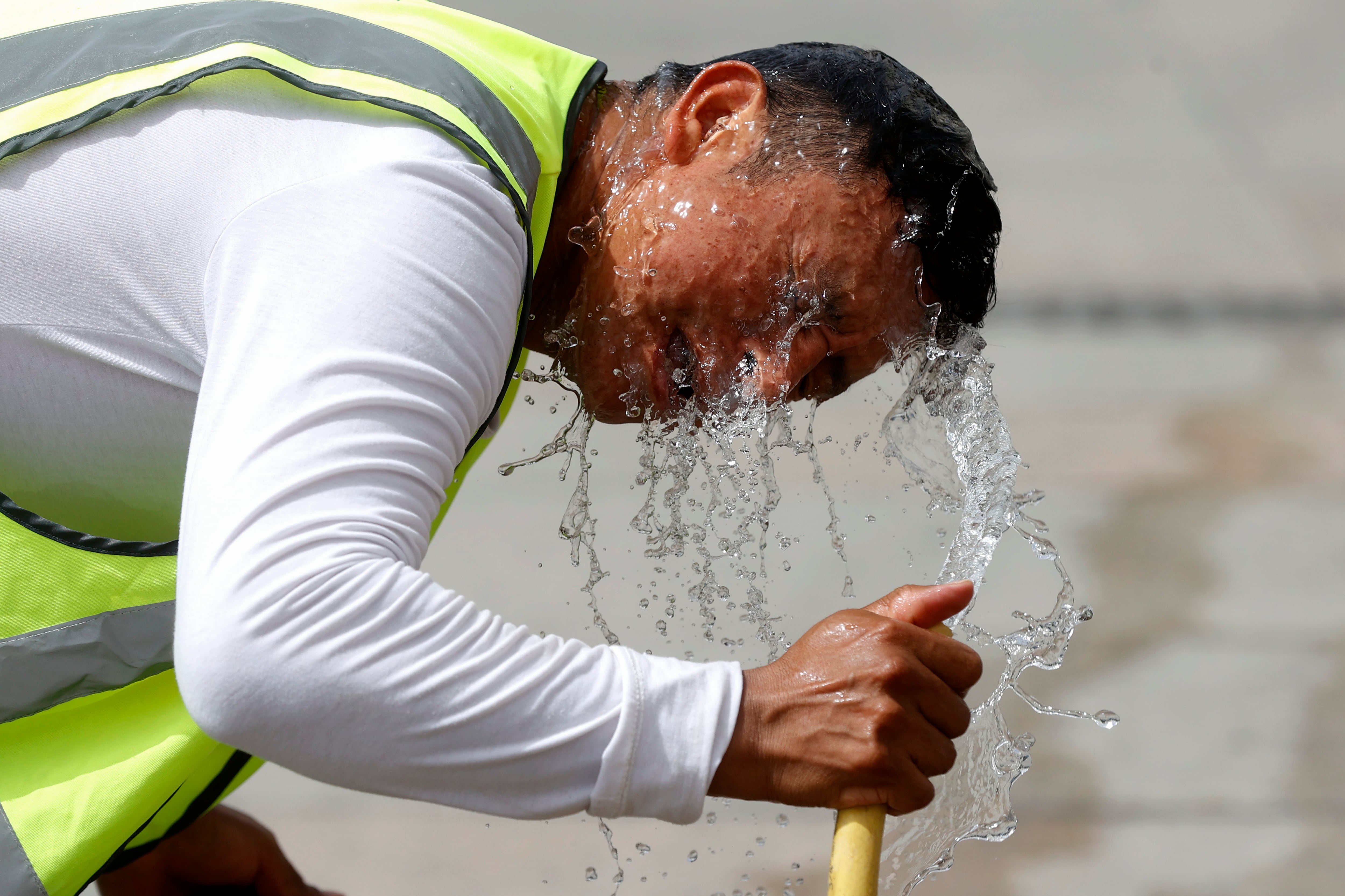 Un trabajador se refresca con una manguera en una calle de Madrid