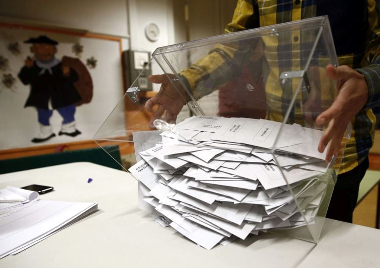 El presidente de una mesa electoral deposita los votos de la urna sobre una mesa