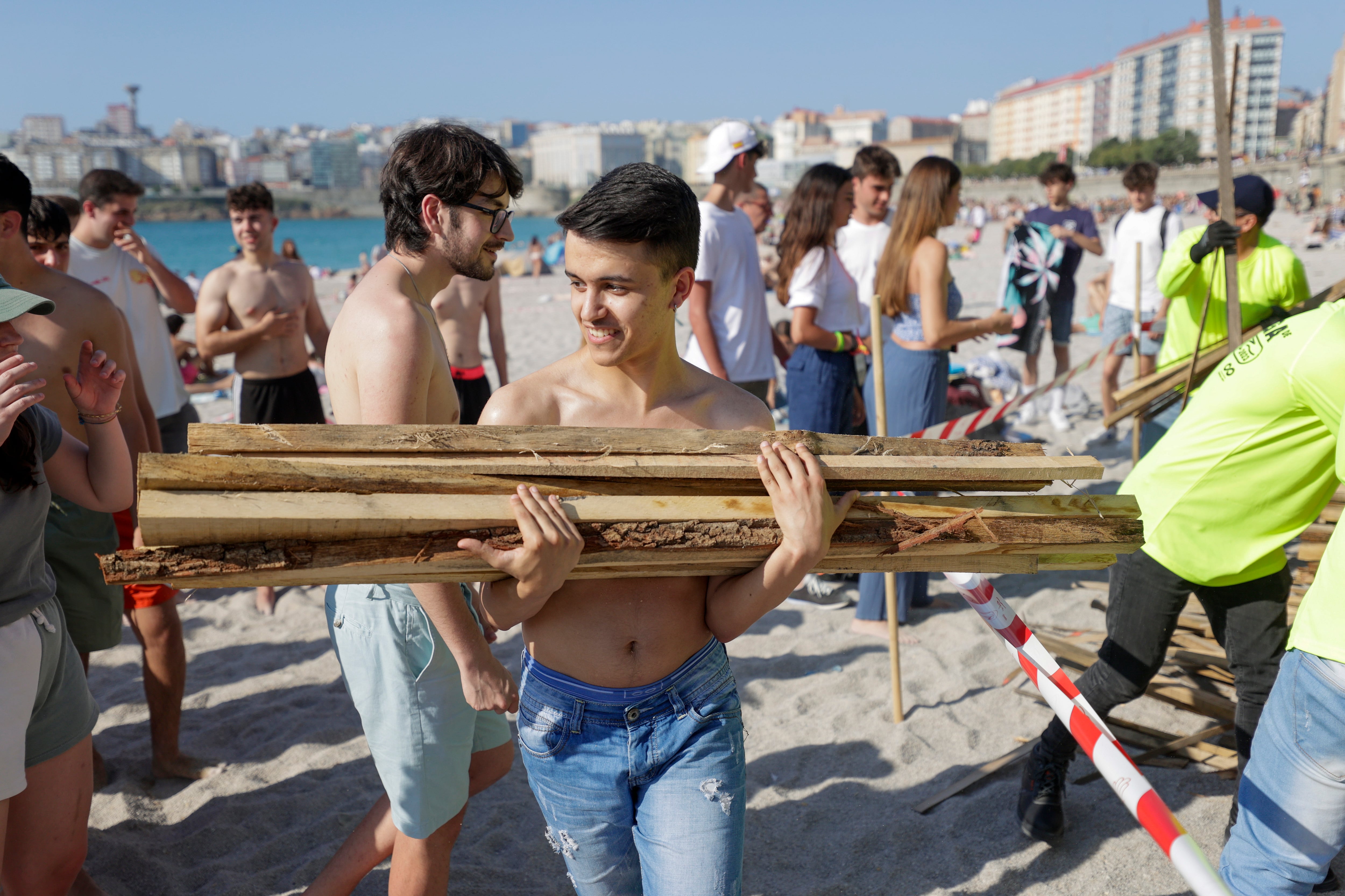 A CORUÑA, 23/06/23.- Una persona carga madera para las hogueras este viernes, en A Coruña. La ciudad de A Coruña vive este viernes su fiesta más multitudinaria, la mágica noche de San Juan, en la que se espera que cientos de miles de personas estén en el entorno de las playas sobre la medianoche para en ellas participar en las tradicionales hogueras. EFE/Cabalar