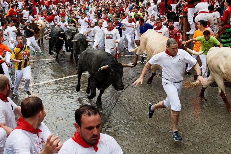 Mozos y toros en el tramo de Telefónica a punto de entrar en el callejón de la Plaza en el segundo encierro de los Sanfermines de 2018