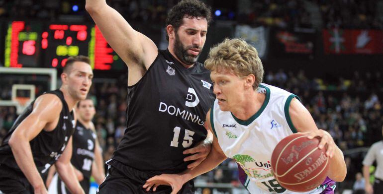 GRA490. BILBAO, 24/05/2015.- El alero del Dominion Bilbao Basket Álex Mumbrú (c) intenta bloquear al alero lituano del Unicaja Mindaugas Kuzminskas, durante el partido de la trigésimo cuarta jornada de Liga que disputan en el Bilbao Arena. EFE/LUIS TEJIDO.