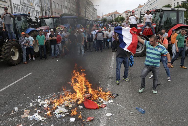 GRA339. SANTIAGO DE COMPOSTELA, 08/09/2015.- Centenares de ganaderos queman una bandera alemana y productos lácteos franceses para protestar por la situación que vive el sector por los bajos precios de la leche, esta tarde en Santiago de Compostela. EFE/Lavandeira jr