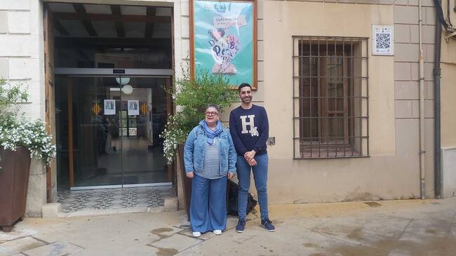 La bibliotecària Carmina Prats i el regidor de Cultura, Fernando Picó, davant del cartell de la Festa del Llibre al poc de ser descobert en la façana de l'Ajuntament
