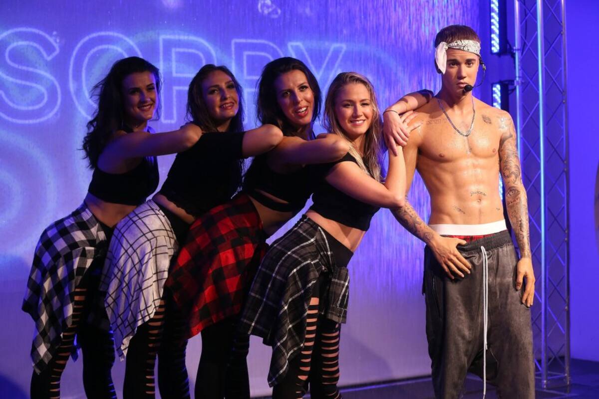 Cuatro fans posan junto a la figura de cera del cantante.