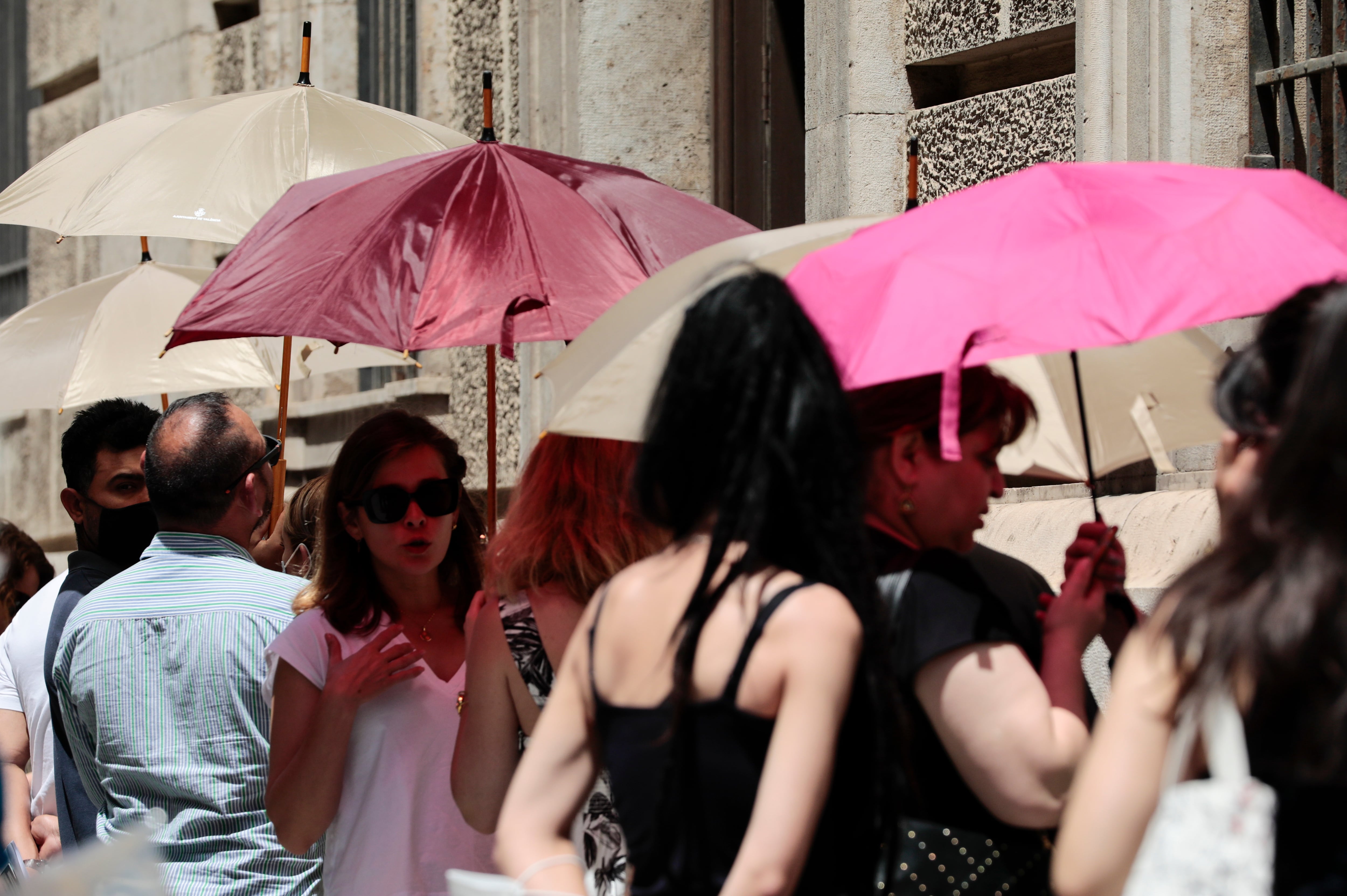 Varias personas se protegen del calor con parasoles