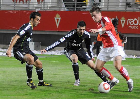 El centrocampista del Real Murcia Daniel Aquino controla el balón entre los defensas del Real Madrid Álvaro Arbeloa y Raúl Albiol