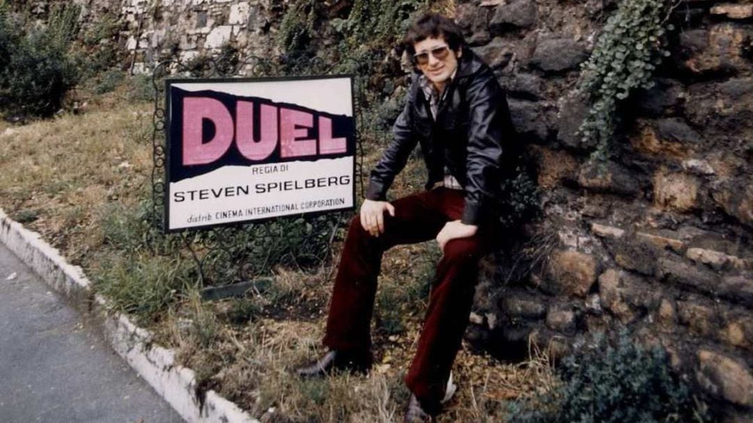 Steven Spielberg junto a un cartel de promoción de Duel (El diablo sobre ruedas) 