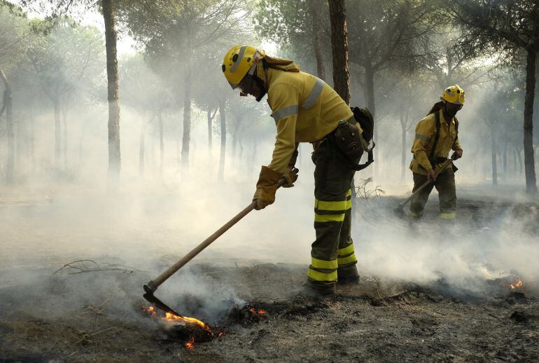 Bomberos trabajan en los alrededores de Mazagón, en Huelva, en el incendio declarado ayer en el término municipal de Moguer que ha obligado a desalojar a más de 2.000 personas y que continúa acechando el Espacio Natural de Doñana