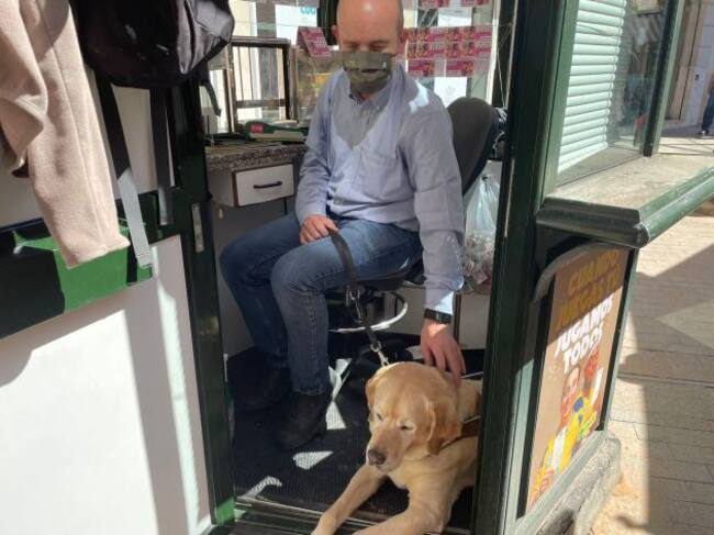 Paco Clemente, vendedor de cupones en la Plaza de las Flores (Murcia), junto a su perro guía, un labrador llamado Hamlet