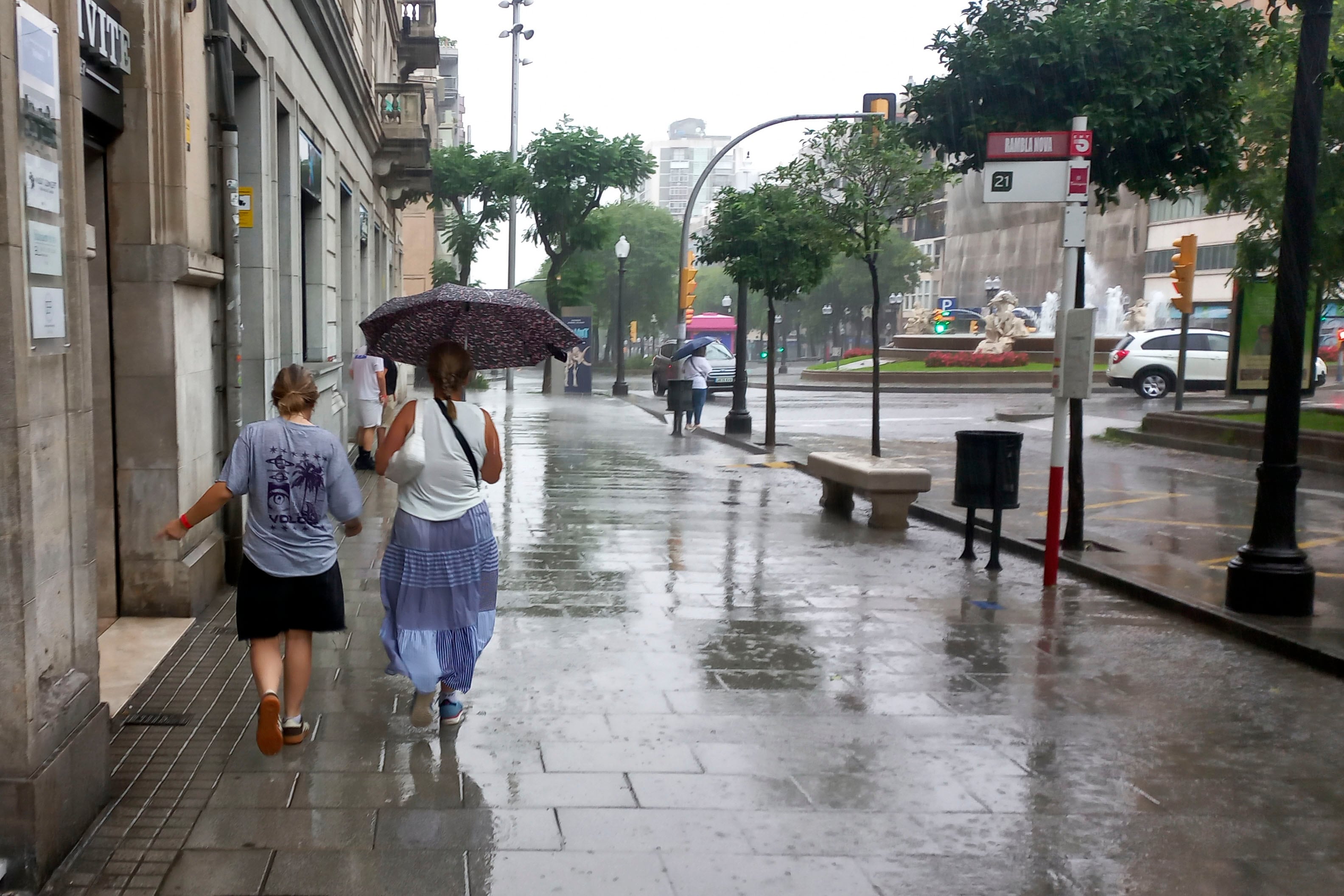 Dos personas se protegen de la lluvia en el centro de Tarragona, el 12 de julio de 2025. EFE/Javier Díaz.