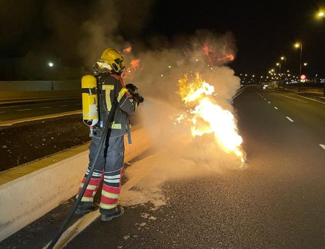 Uno de los bomberos del Consorcio de Seguridad y Emergencias de Lanzarote, sofocando el incendio de un contenedor en plena calzada de la LZ-1.