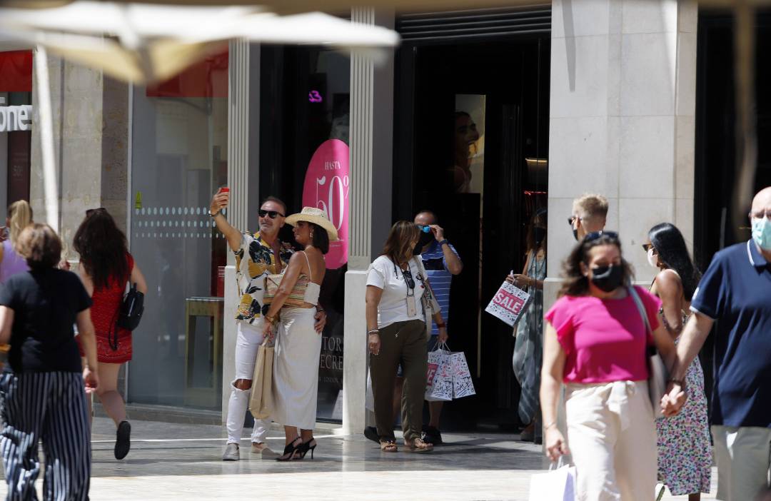 Personas sin mascarilla y otras con mascarilla en la calle Larios, durante el primer día en el que no es obligado el uso de la mascarilla en exteriores desde el inicio de la pandemia, a 26 de junio de 2021, en Málaga 