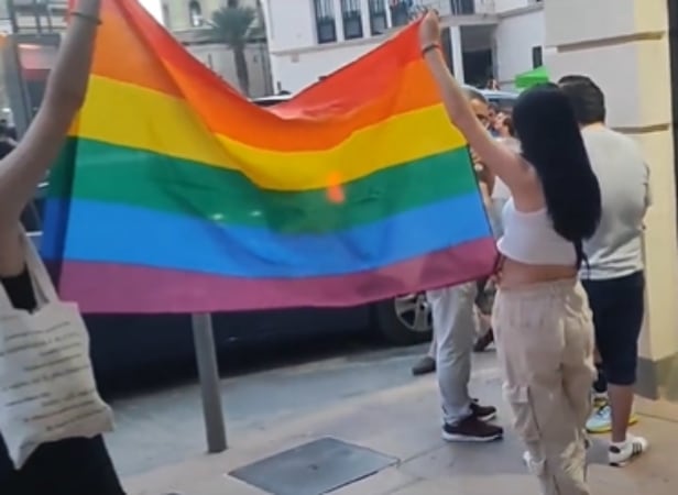 Unos jóvenes sacan la bandera arcoíris en el mitin