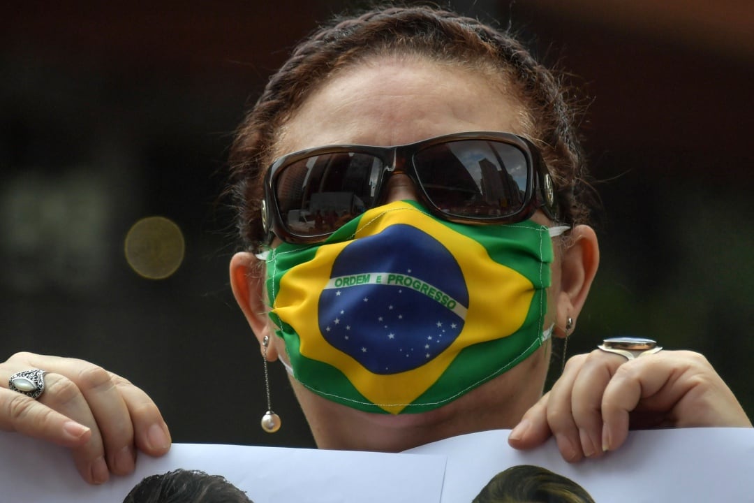 Una partidaria del presidente brasileño, Jair Bolsonaro, con una mascarilla de la bandera brasileña, participa en una protesta contra la cuarentena y las medidas de distanciamiento social impuestas para combatir el nuevo brote de coronavirus, en el Día de los Trabajadores, en São Paulo, el 1 de mayo. 2020