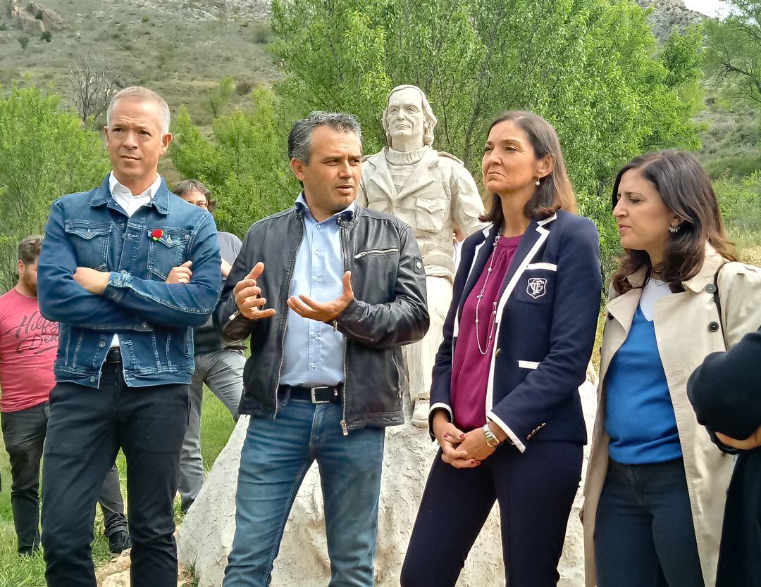 La ministra de Industria y Turismo, Reyes Maroto, escucha las explicaciones del alcalde de Poza de la Sal, José Tomás López, en presencia de los parlamentarios socialistas Ander Gil y Esther Peña y delante del monumento a Félix Rodríguez de la Fuente