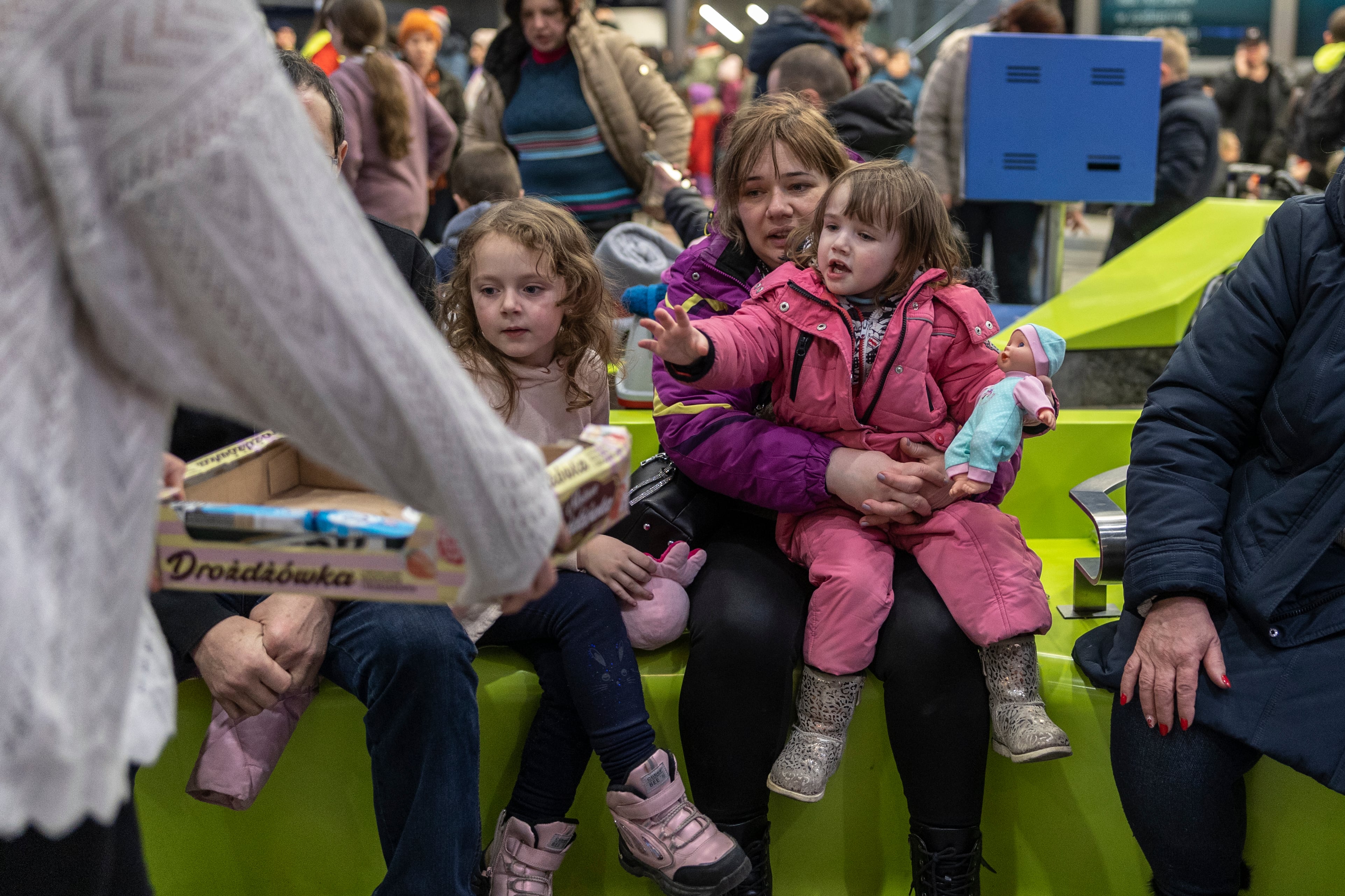 Decenas de refugiados procedentes de Ucrania esperan en la estación de tren de Cracovia, Polonia, mientras grupos de voluntarios reparten comida y bebida.