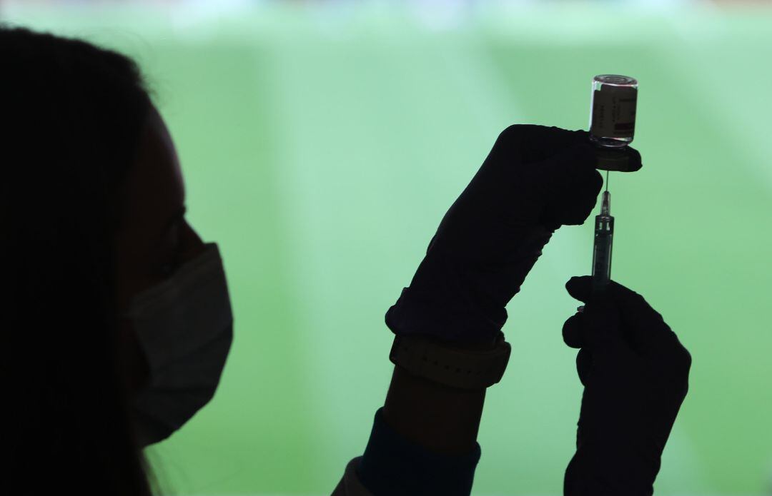 Un profesional sanitaria sostiene una jeringuilla y un vial con la vacuna del Covid-19, en un dispositivo instalado en el Estadio Wanda Metropolitano