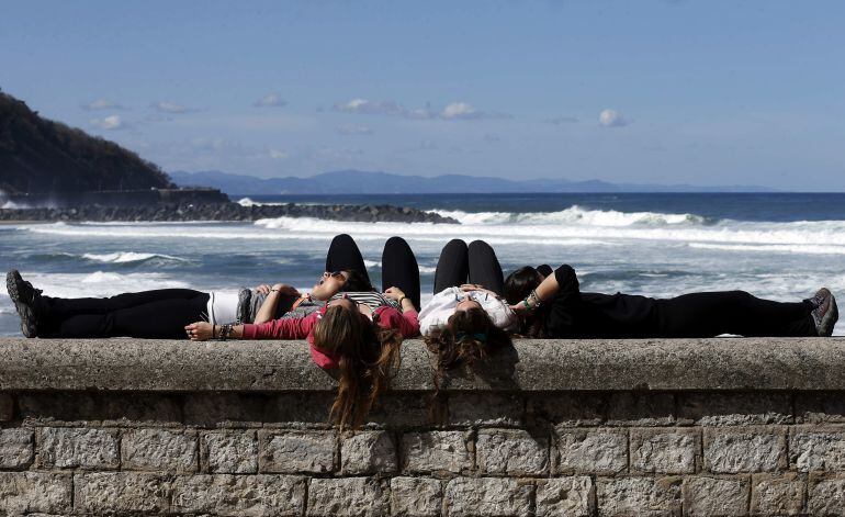 Varias jóvenes toman el sol junto a la playa de La Zurriola de San Sebastián esta semana