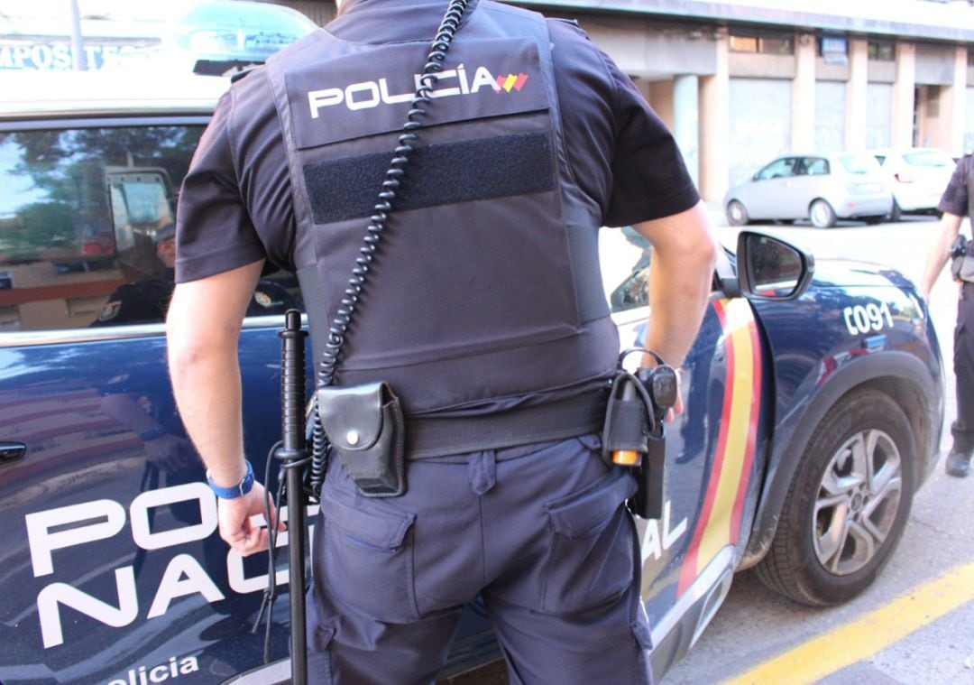 Agente de la Policía Nacional junto a un vehículo policial (archivo)