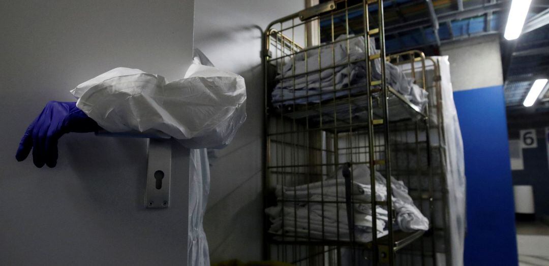 Ropa laboral en un hospital mientras que un profesional sujeta una puerta.