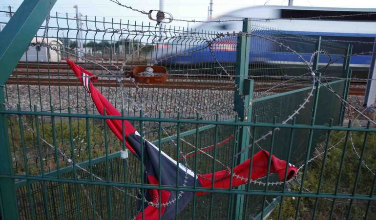 Un tren de alta velocidad pasa por delante de una de las vallas de seguridad recubierta por alambre de pinchos, que protegen el Eurotúnel.