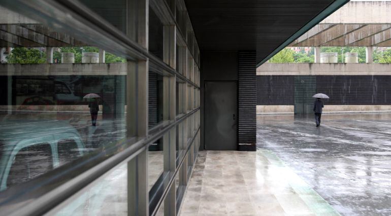 Un hombre pasea bajo la lluvia en el Museo de la Ciencia