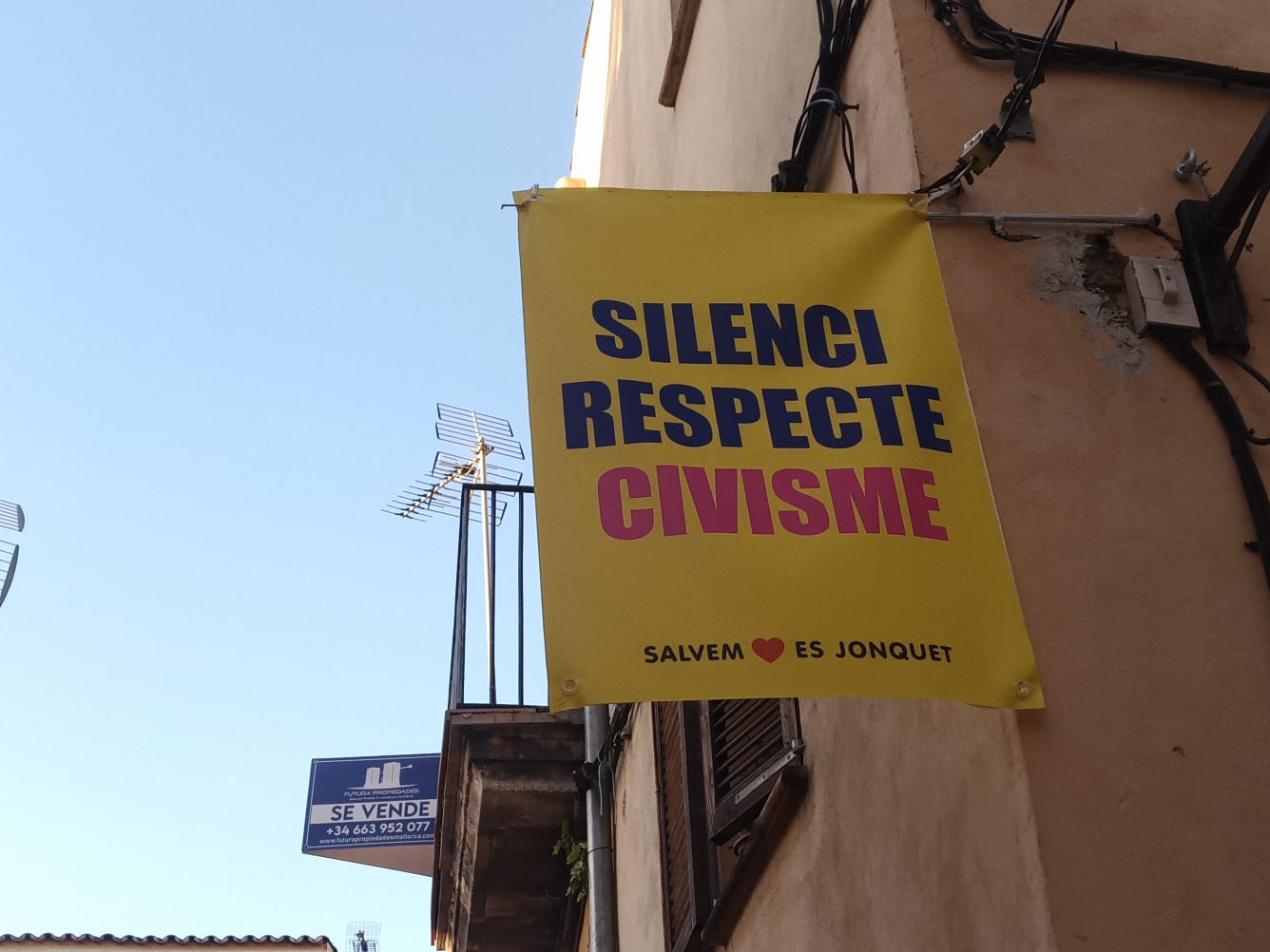 Carteles desplegados por el barrio que piden civismo, justo detrás un letrero de &quot;se vende&quot;.