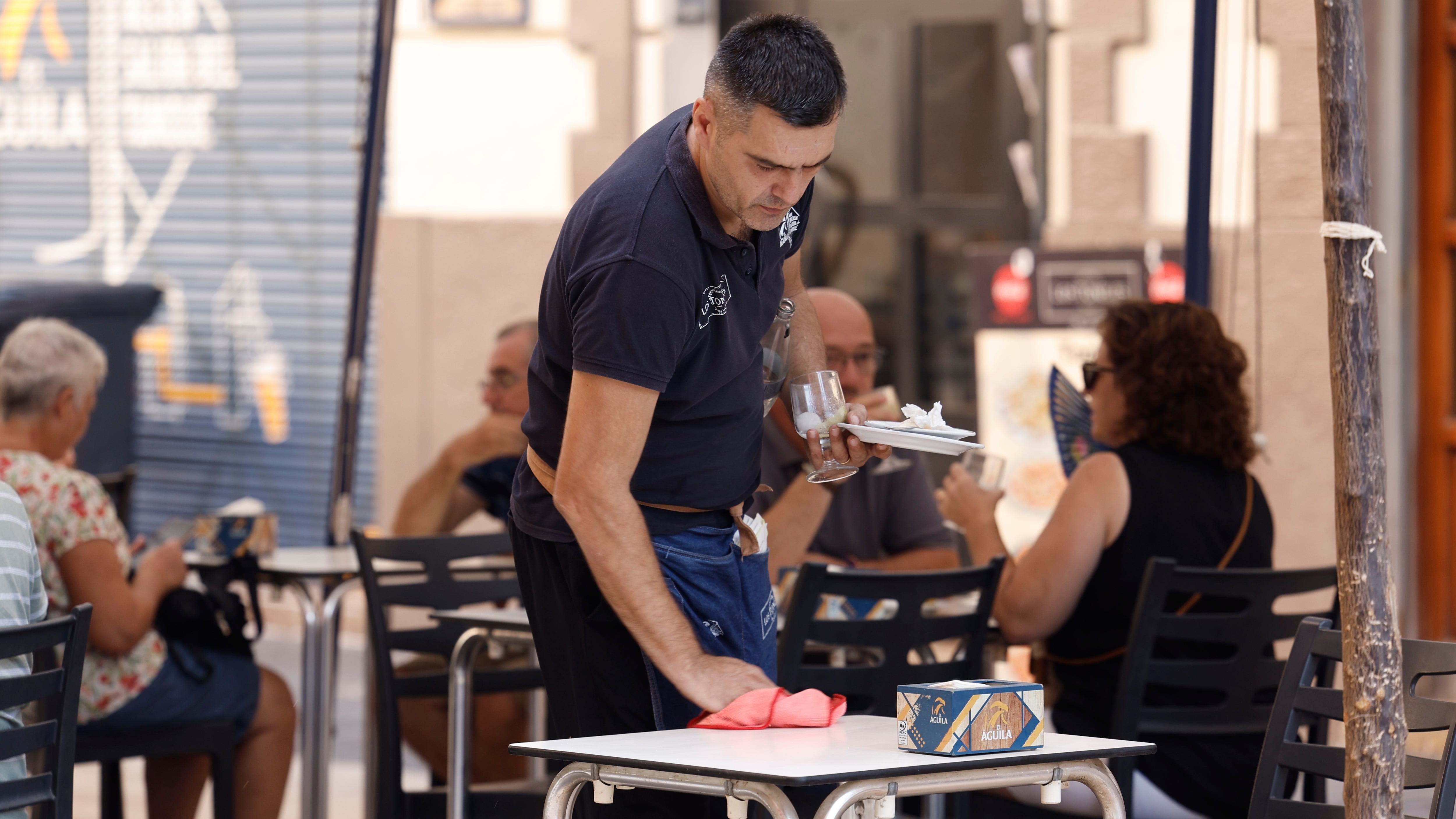 Un camarero limpia la mesa de una terraza de un bar en una imagen de archivo