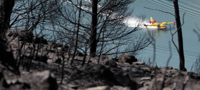 Un hidroavión recarga agua en el pantano de Benagéber durante las tareas de extinción del incendio forestal que se declaró ayer viernes en Tuéjar.