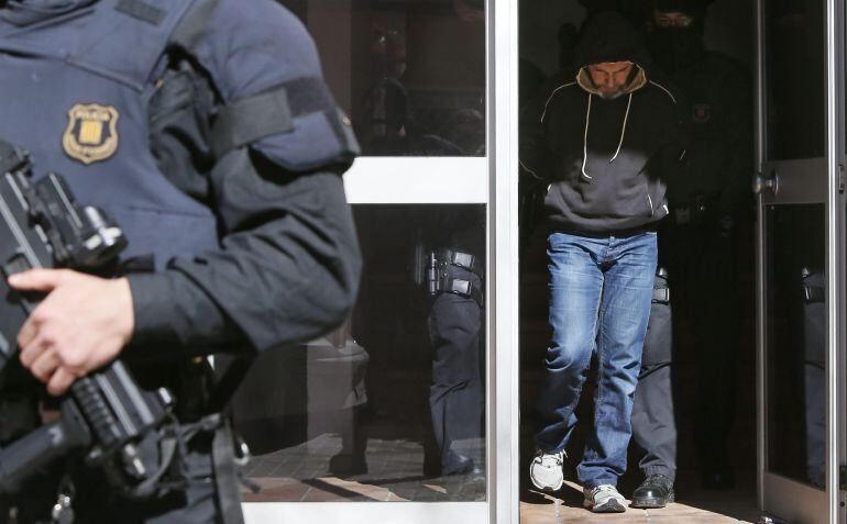 Agentes de los Mossos d&#039;Esquadra custodian a una de las once personas que han sido detenidas en el marco de una operación contra el terrorismo yihadista llevada a cabo por la policía catalana, coordinada por el juzgado número 1 de la Audiencia Nacional